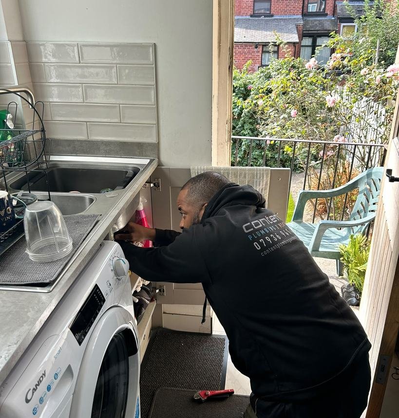 Daniel Sheriffe of Content Plumbing and Heating working on pipework under a kitchen sink in Leeds