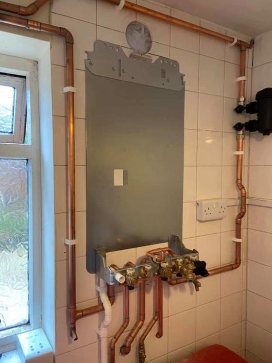 Boiler backplate and new copper pipework first-fixed to a tiled wall, with the magnetic system filter fitted