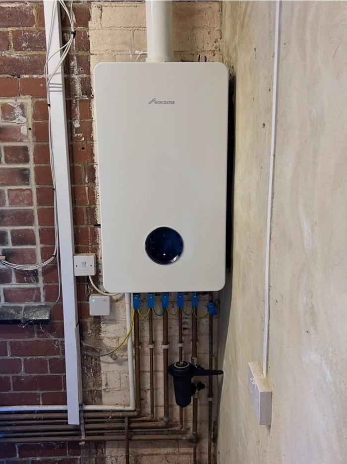 A Worcester Bosch boiler installed and commissioned on an exposed brick wall, with the system filter fitted below